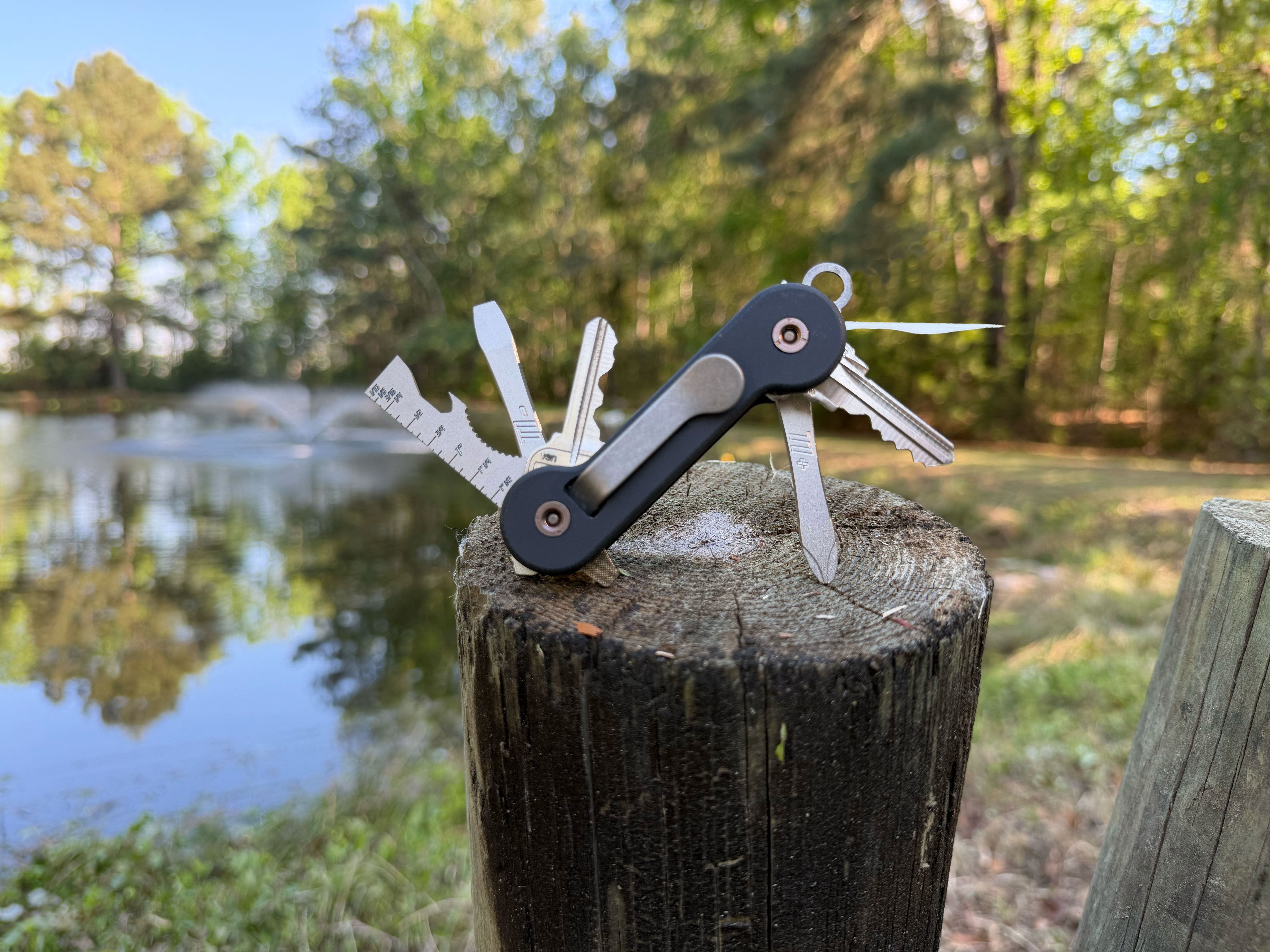 Black-G10-with-titanium-pick_-multi-tool_-phillips-and-flathead-screwdrivers-open-on-wood-pylon